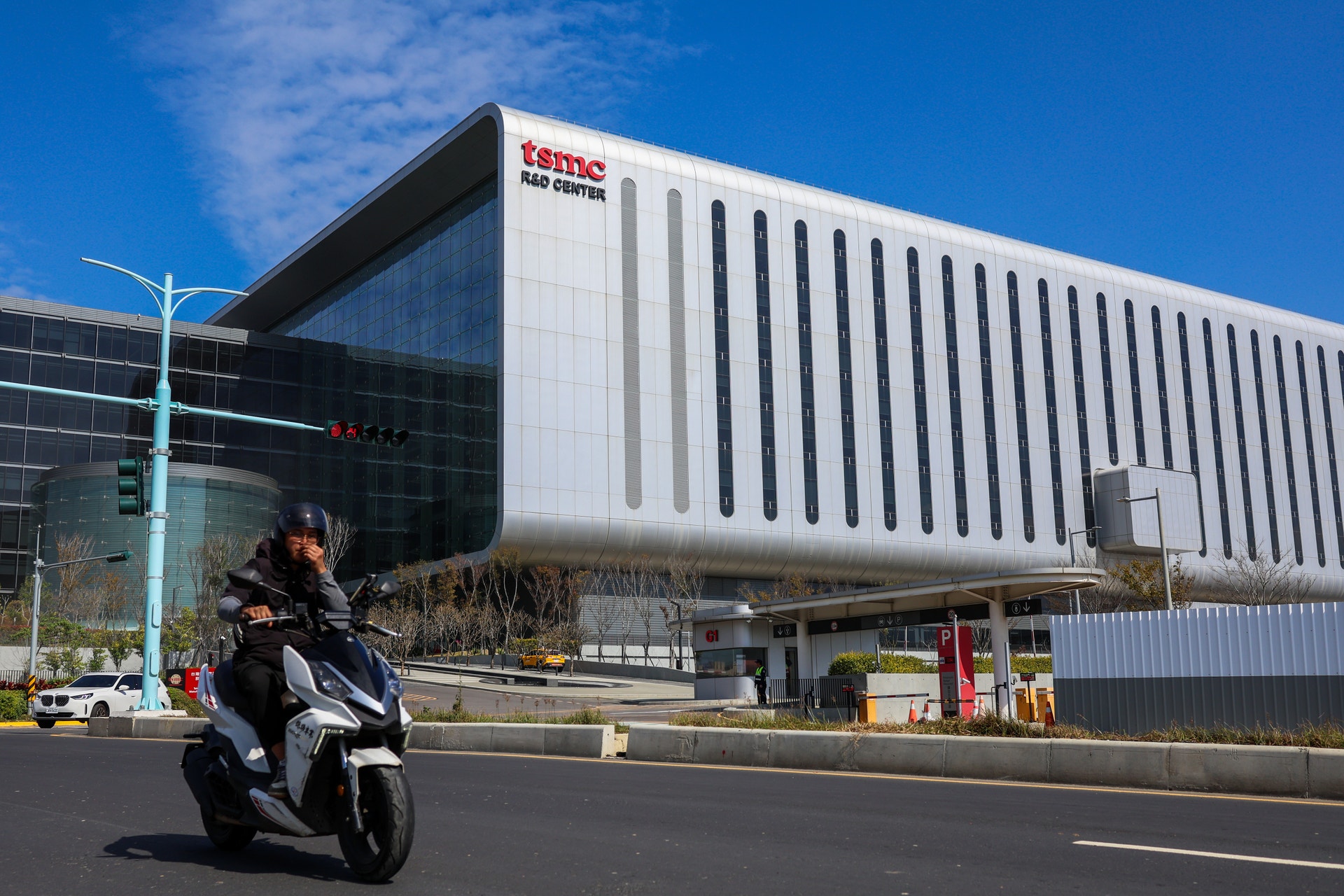 En person på en svart scooter framför en modern vit byggnad med DATA CENTER-skylt.