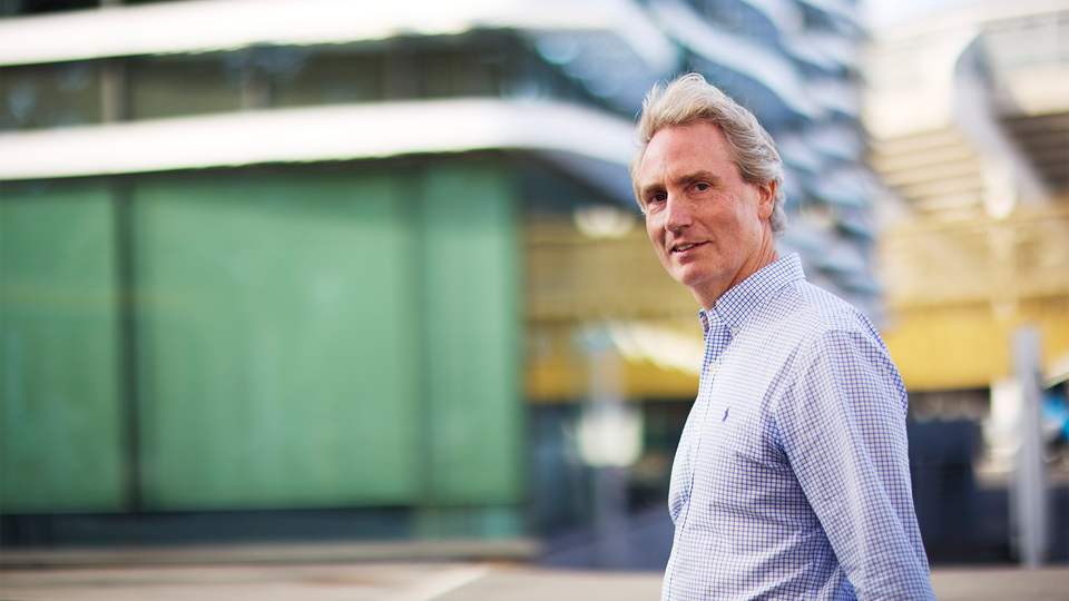 Erik Selin traskar på gatan utanför Balders kontor i Göteborg. Han har blå-vit rutig skjorta.