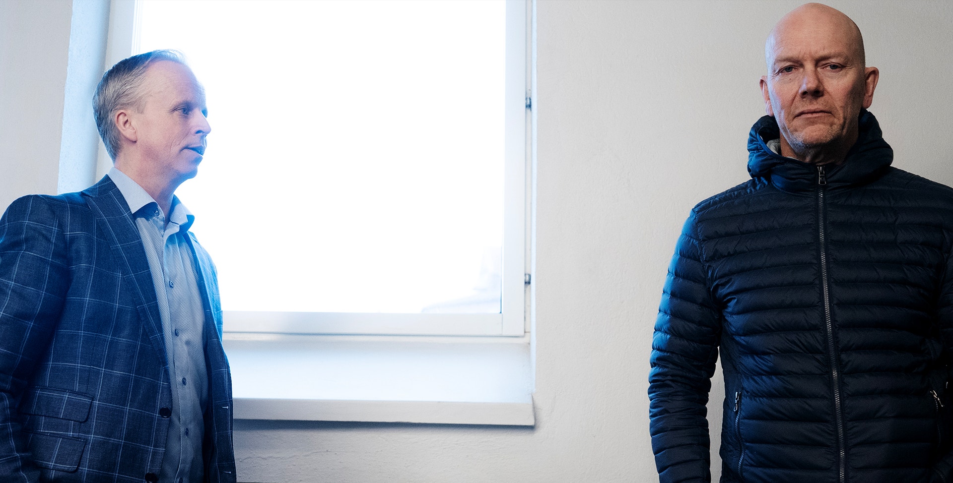Mats Sundin och Mikael Sundström står sida vid sida framför ett fönster. Mats tittar djupt in i kameran.