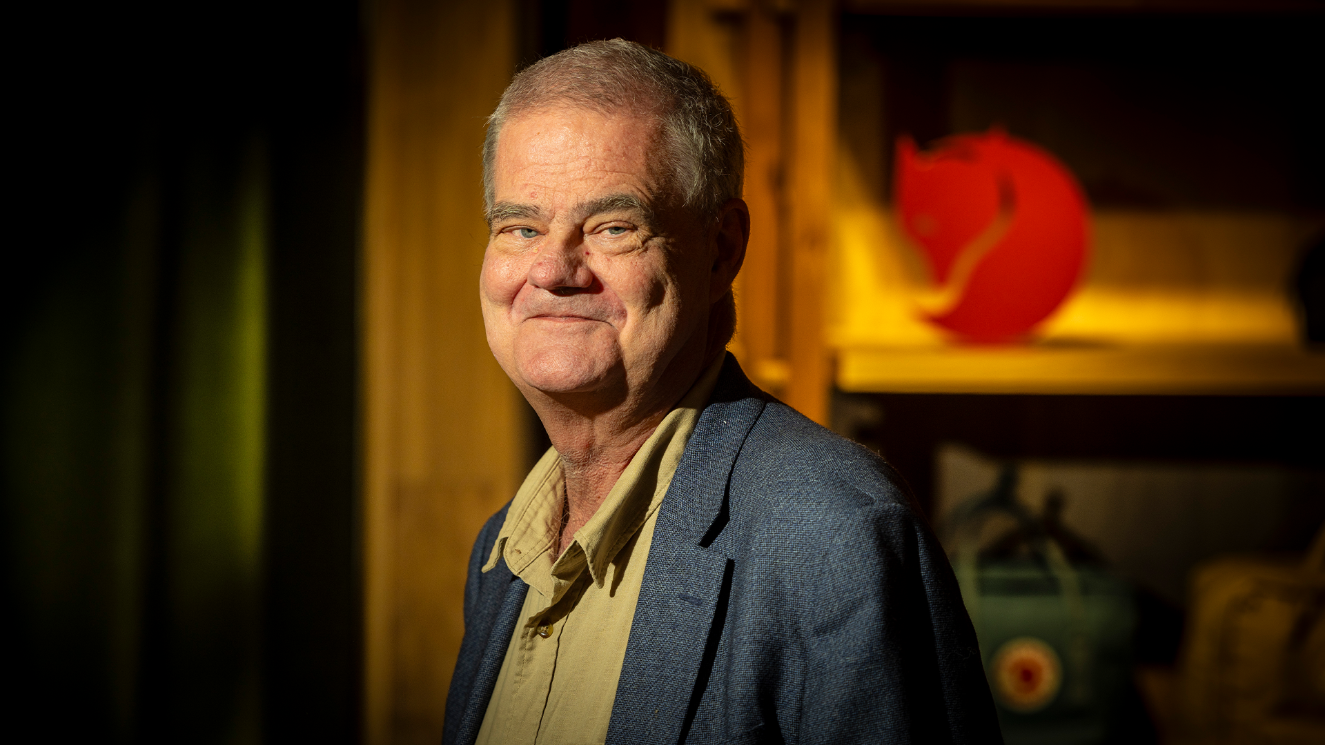 Martin Nordin ler in i kameran. Bakom honom står en fjällräven-räv på en hylla. 