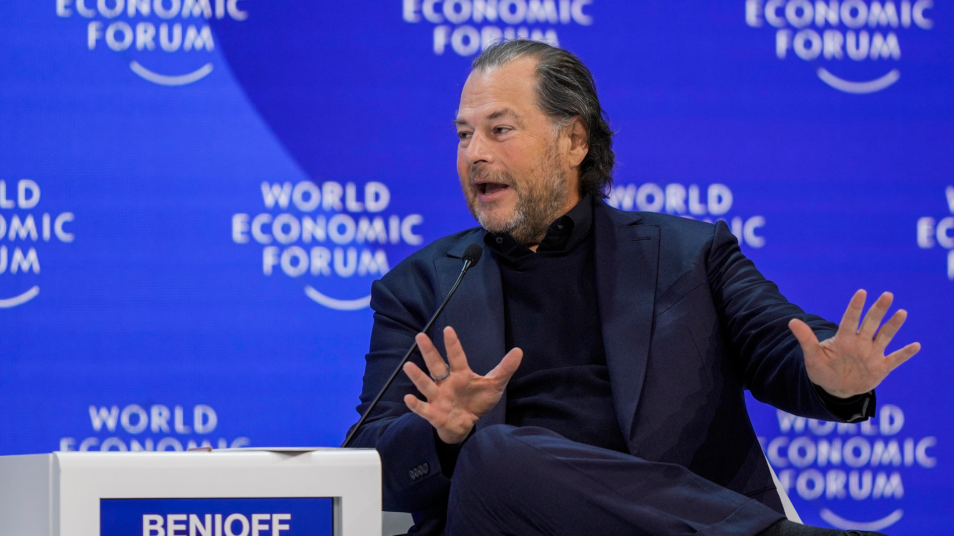 En man talar vid World Economic Forum och gestikulerar medan han presenterar.