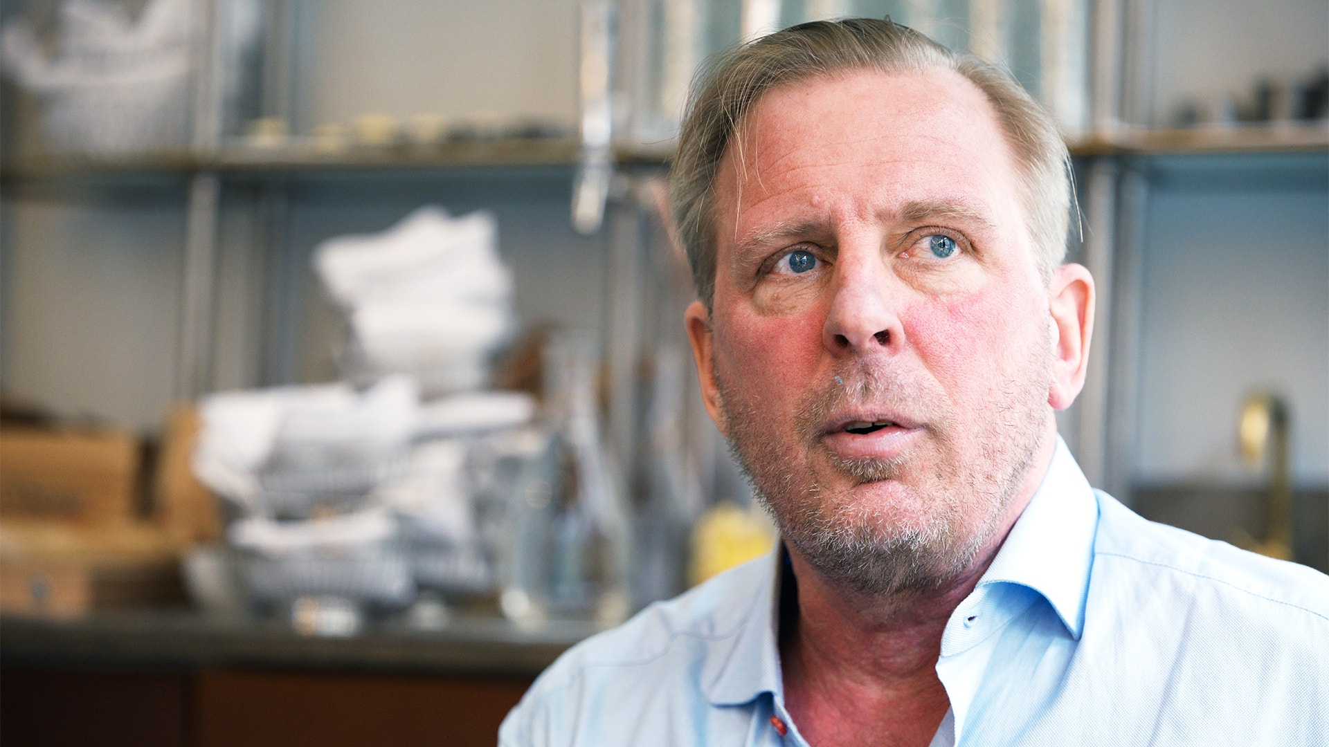 Porträtt av en man i ljusblå skjorta framför en bokhylla