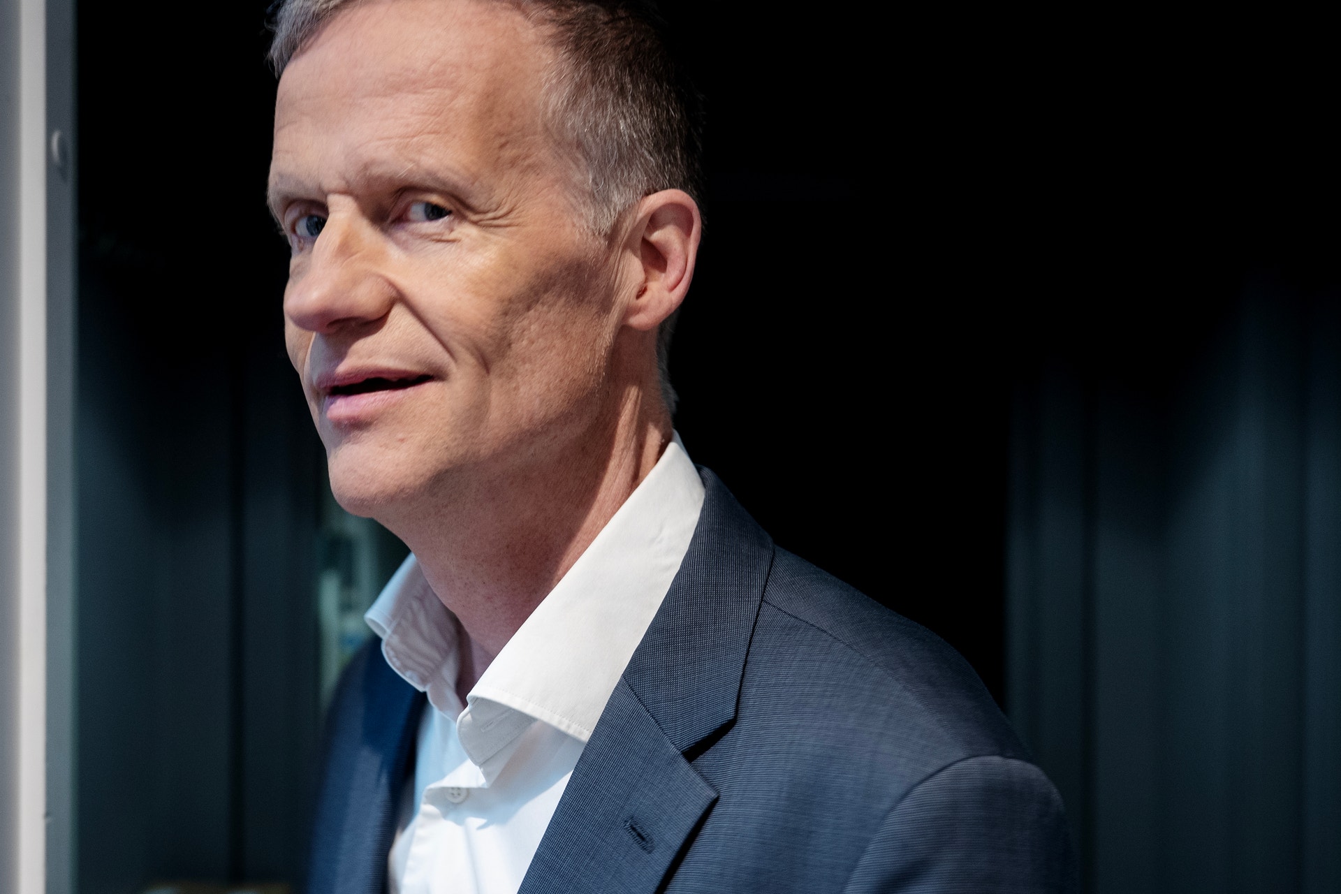 Porträtt av en man i mörkblå kostym och vit skjorta