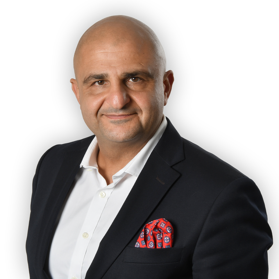 Sharam Rahi i en pressbild. Han ler in i kameran. Ham har svart kavaj, vit skjorta och en röd näsduk i bröstfickan. 