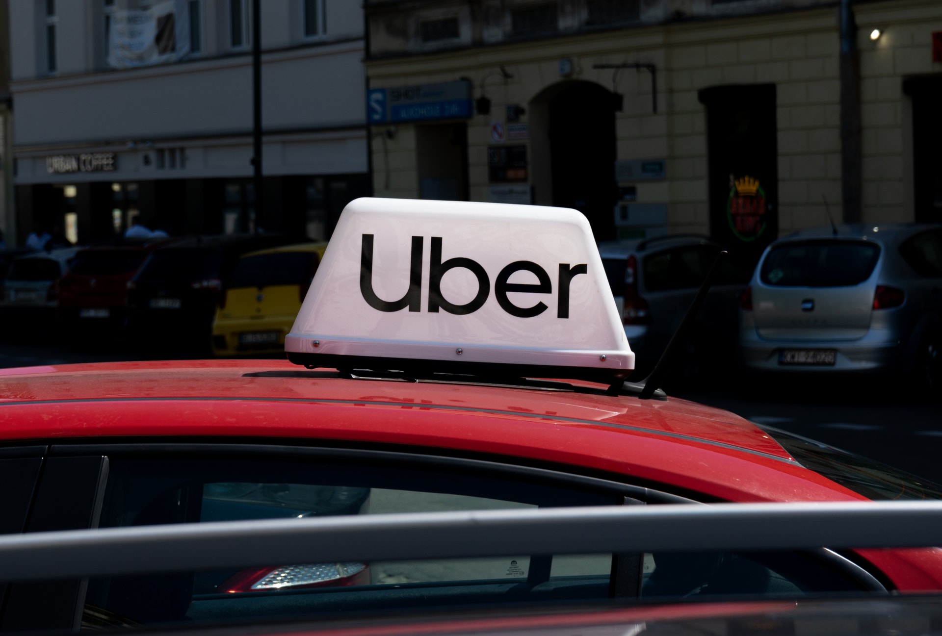 En röd Uber-taxi med vitt märke på taket, parkerad på en stadsgata