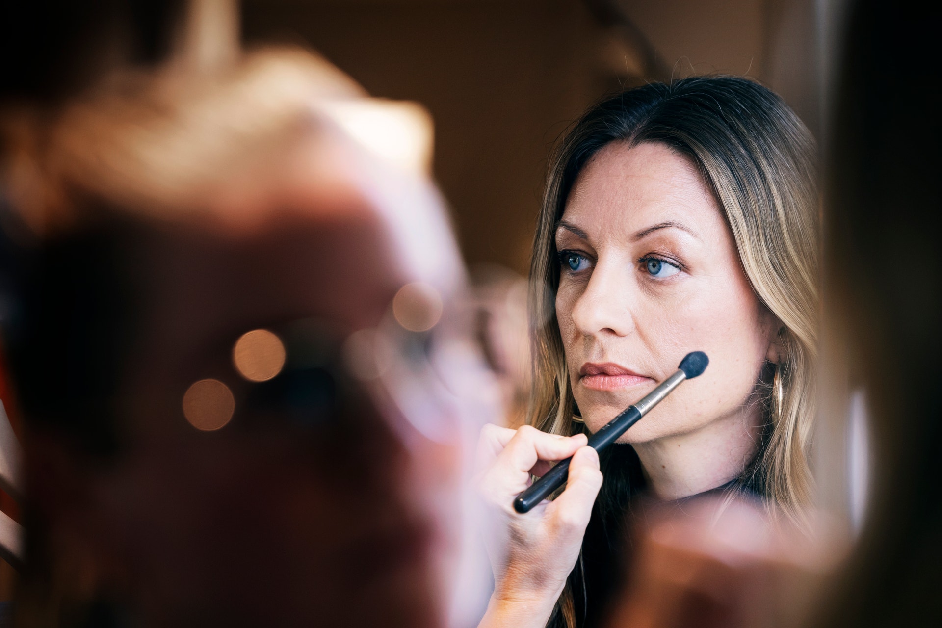 Kvinna får makeup applicerad med en makeuppensil på kinden.