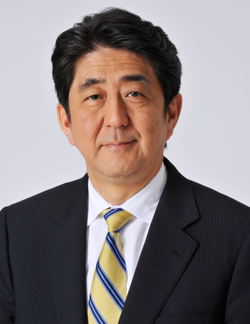 Porträtt av en man i formell affärsdräkt med mörk kostym, vit skjorta och gul-blå slips.