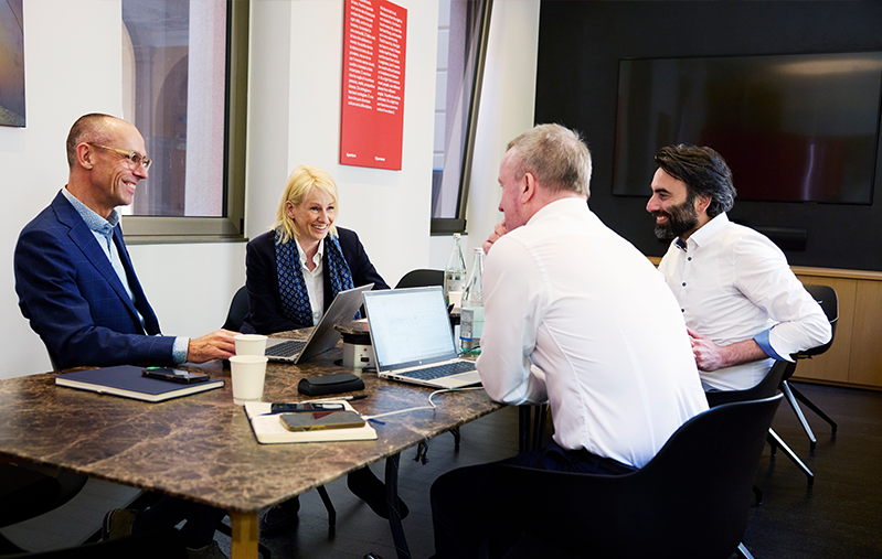 Bodil Sonesson med några kollegor vid ett konferensbord. På bordet står det kaffekoppar och vattenflaskor.