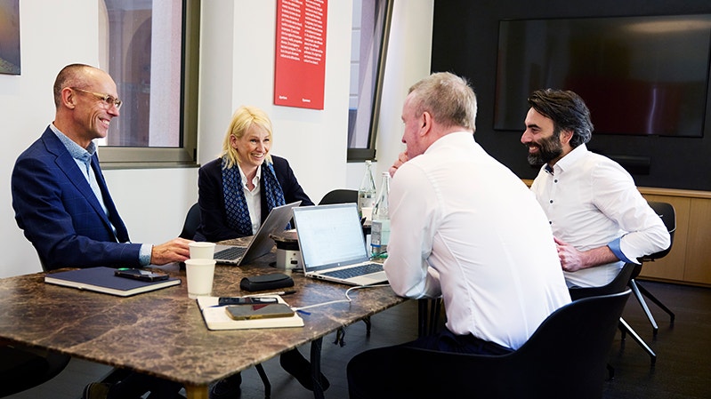 Bodil Sonesson med några kollegor vid ett konferensbord. På bordet står det kaffekoppar och vattenflaskor.