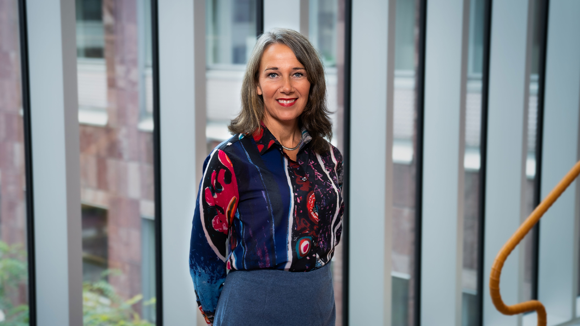 Annika Winsth står i en ljusgång på ett av Nordeas kontor. Hon bär en färgglad blus. 