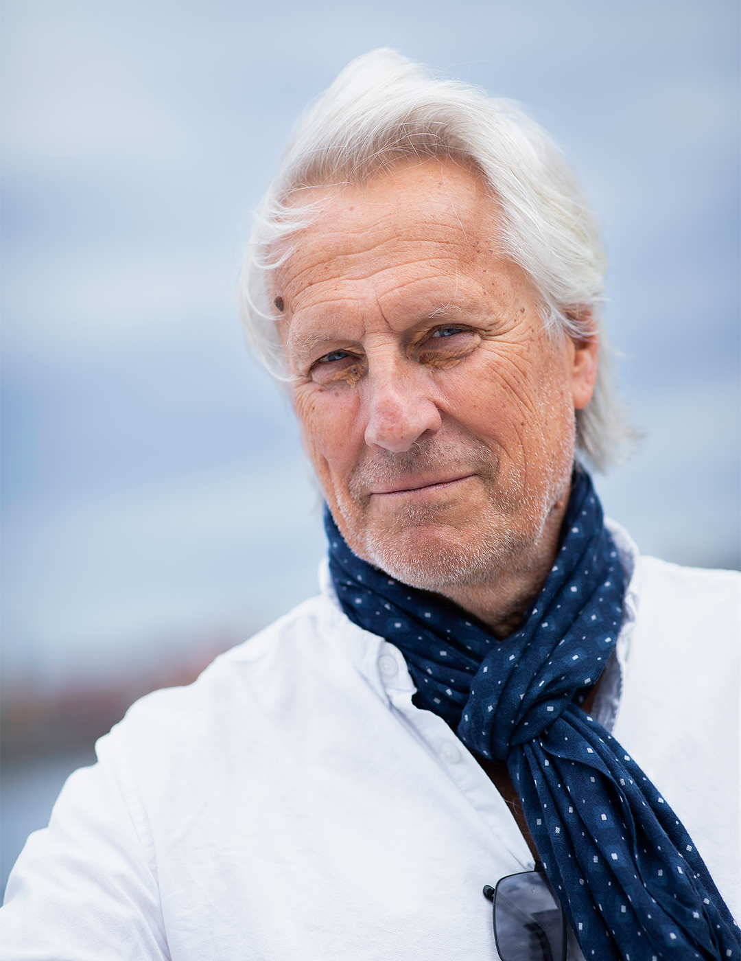 Lars Trägårdh fotas vid en av Stockholms kanaler. Han har märkblå scarf och vit skjorta. 