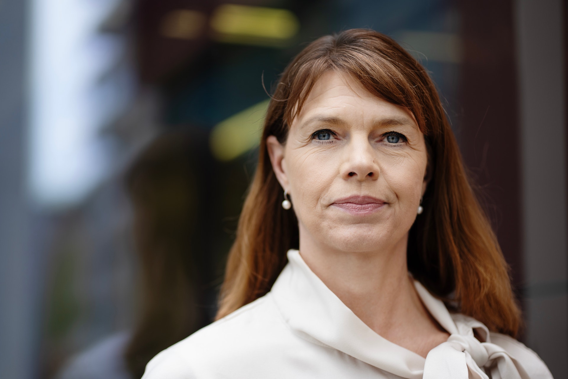 Porträtt av en kvinna med långt rödbrunt hår och vit skjorta.