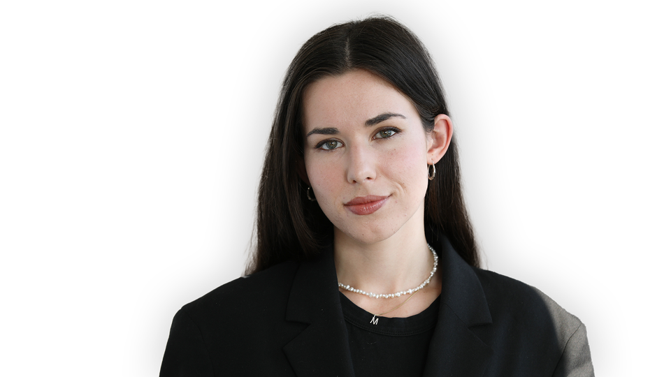 Molly Guggeinheimer tittar in i kameran. Hon har svart kavaj och pärlhalsband.