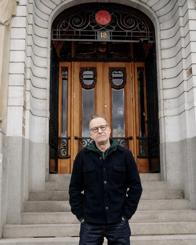 Man står på trappsteg framför en dekorativ träport med nummer 18