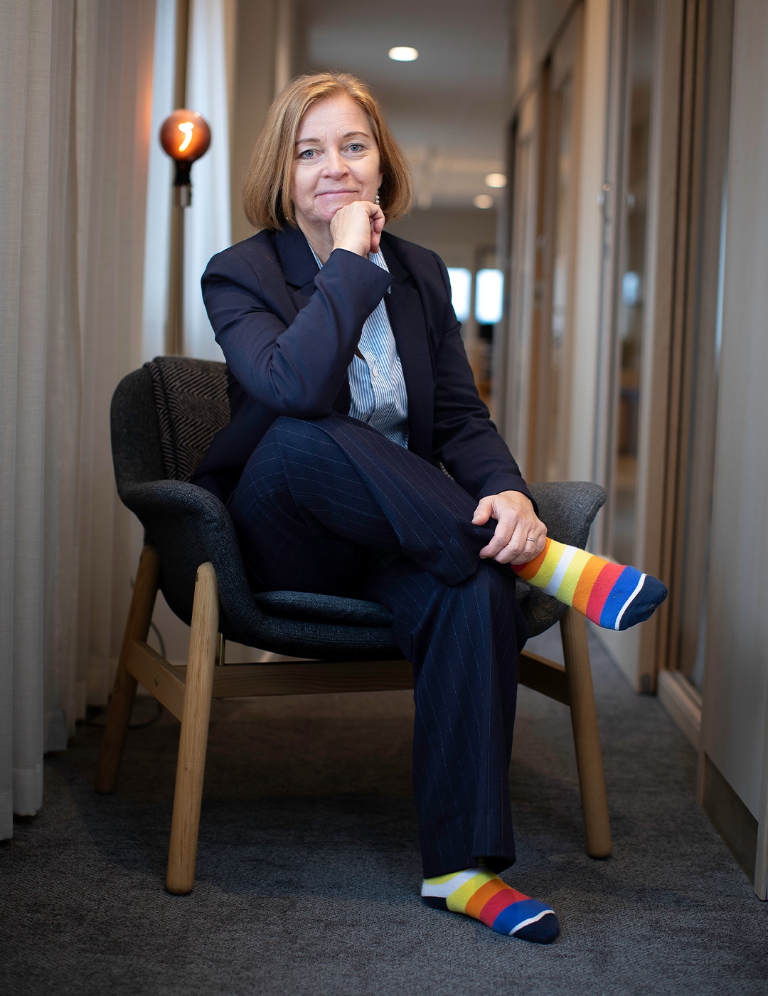 Karin Bodin sitter med färgglada strumpor på en stol i korrridoren.