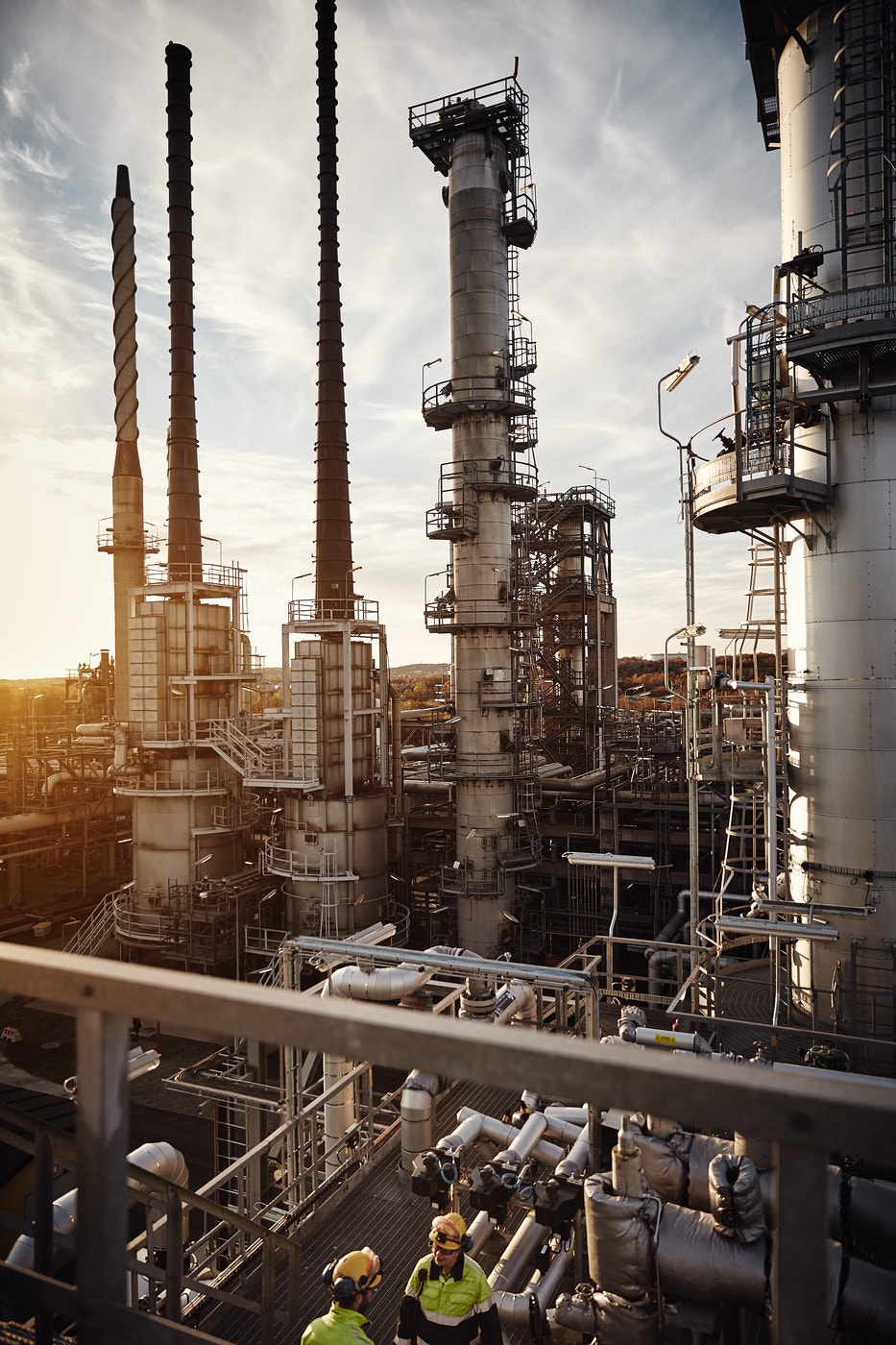 En raffineringsanläggning med höga destillationstorn och industriell utrustning under gyllene solljus.