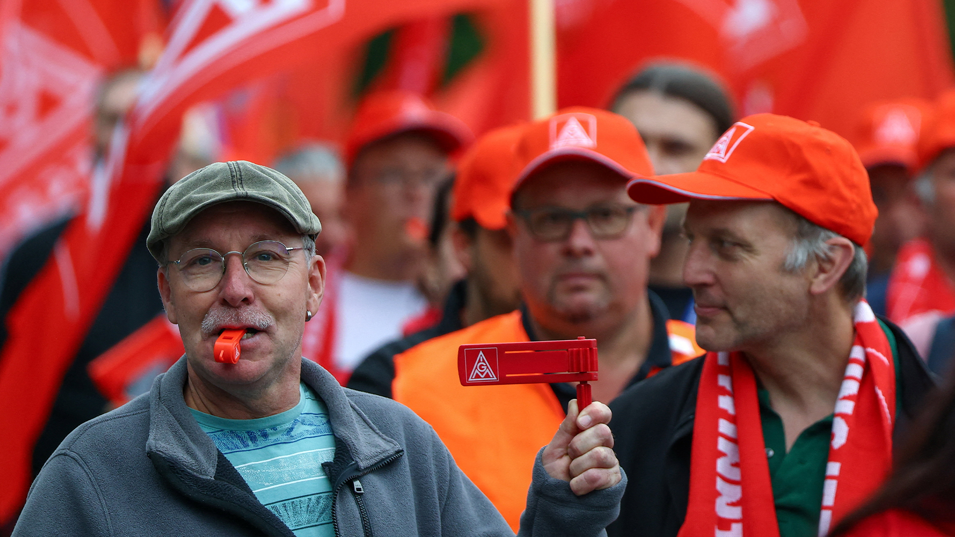Grupp människor på demonstration med röda flaggor och kepsar.
