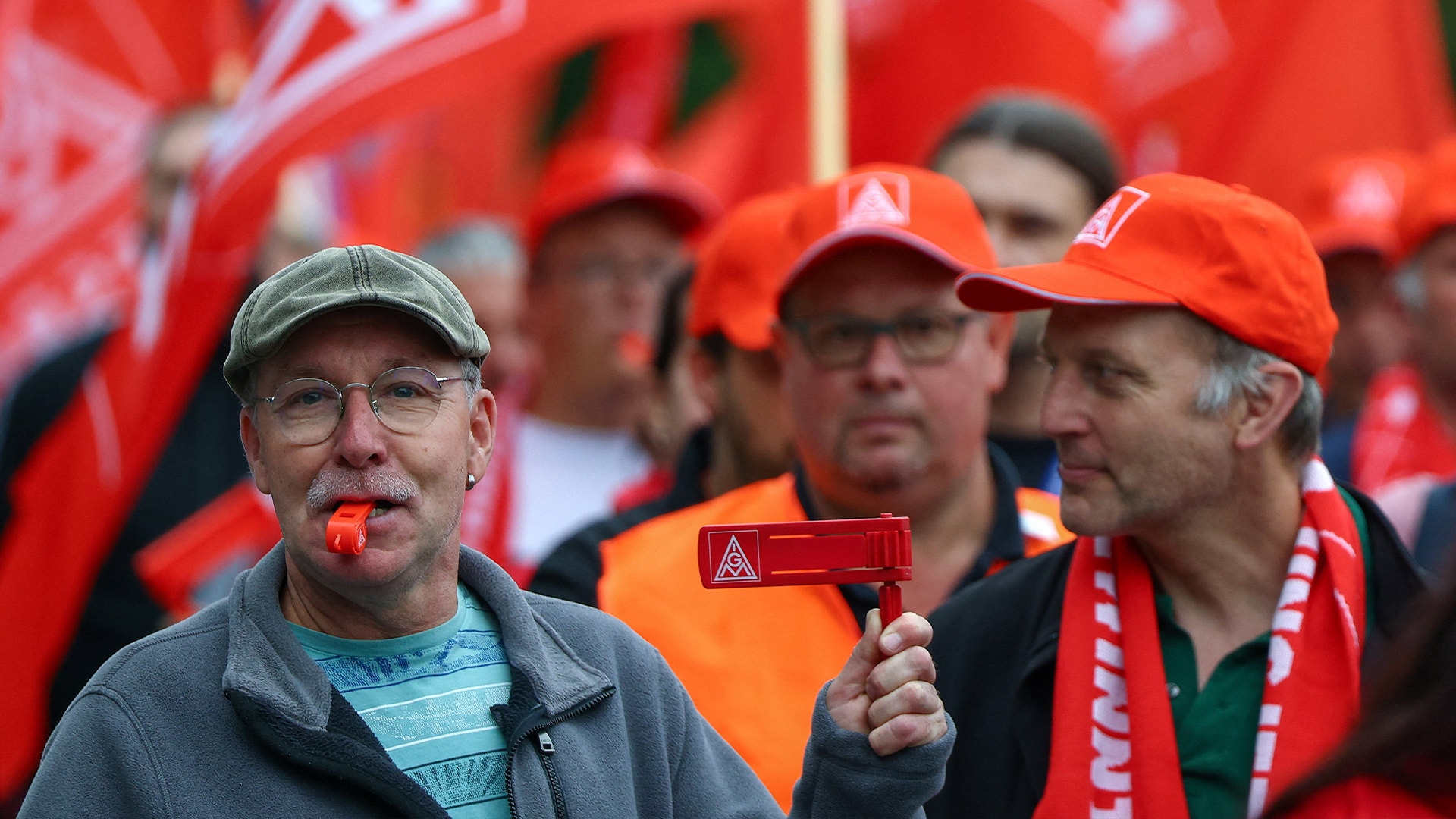 Grupp människor på demonstration med röda flaggor och kepsar.