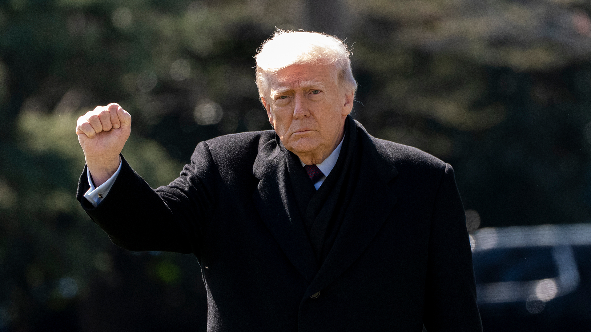 Man i svart kostym med höjd näve