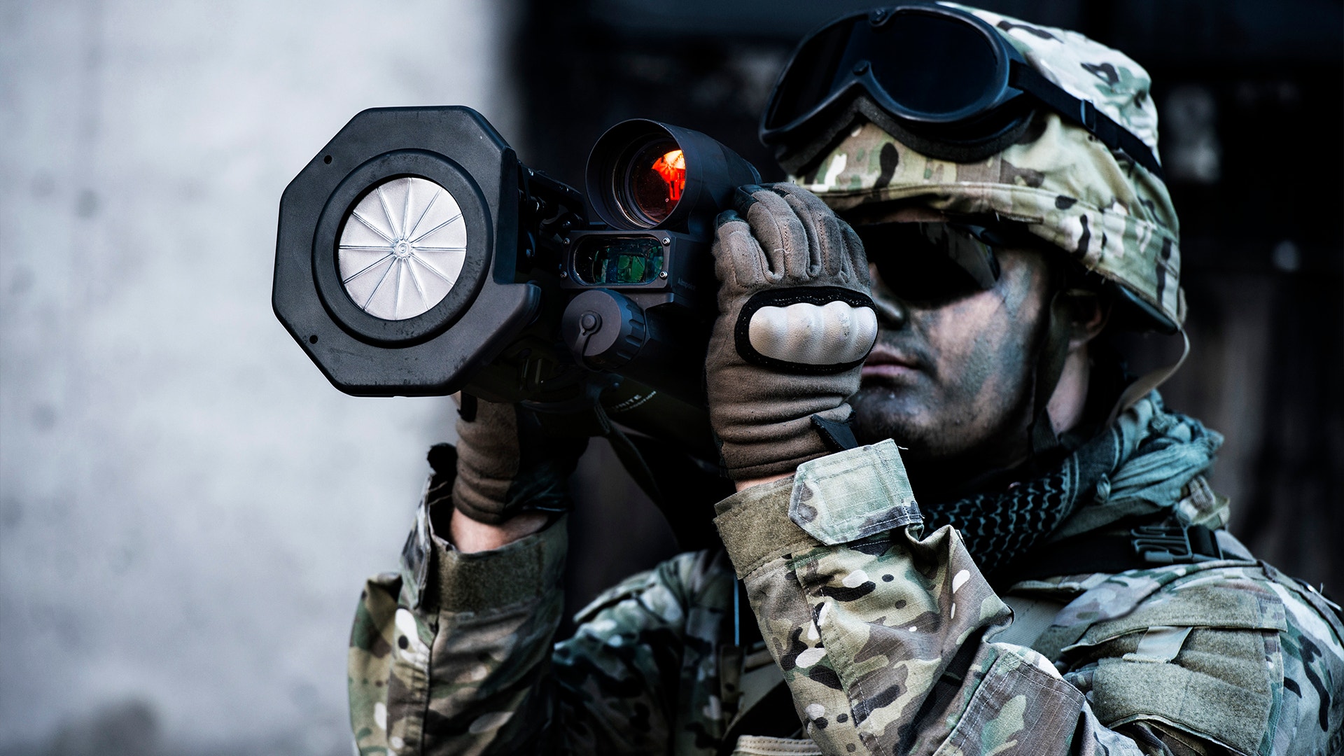 Soldat i kamouflageutrustning siktar med ett vapen utrustat med taktisk optik.