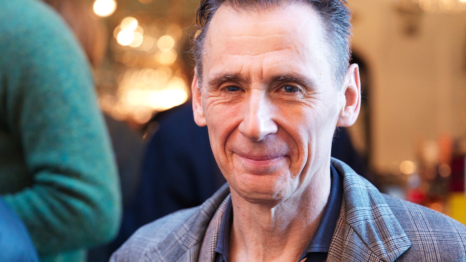 Porträtt av en man i rutad skjorta på ett inomhusevenemang