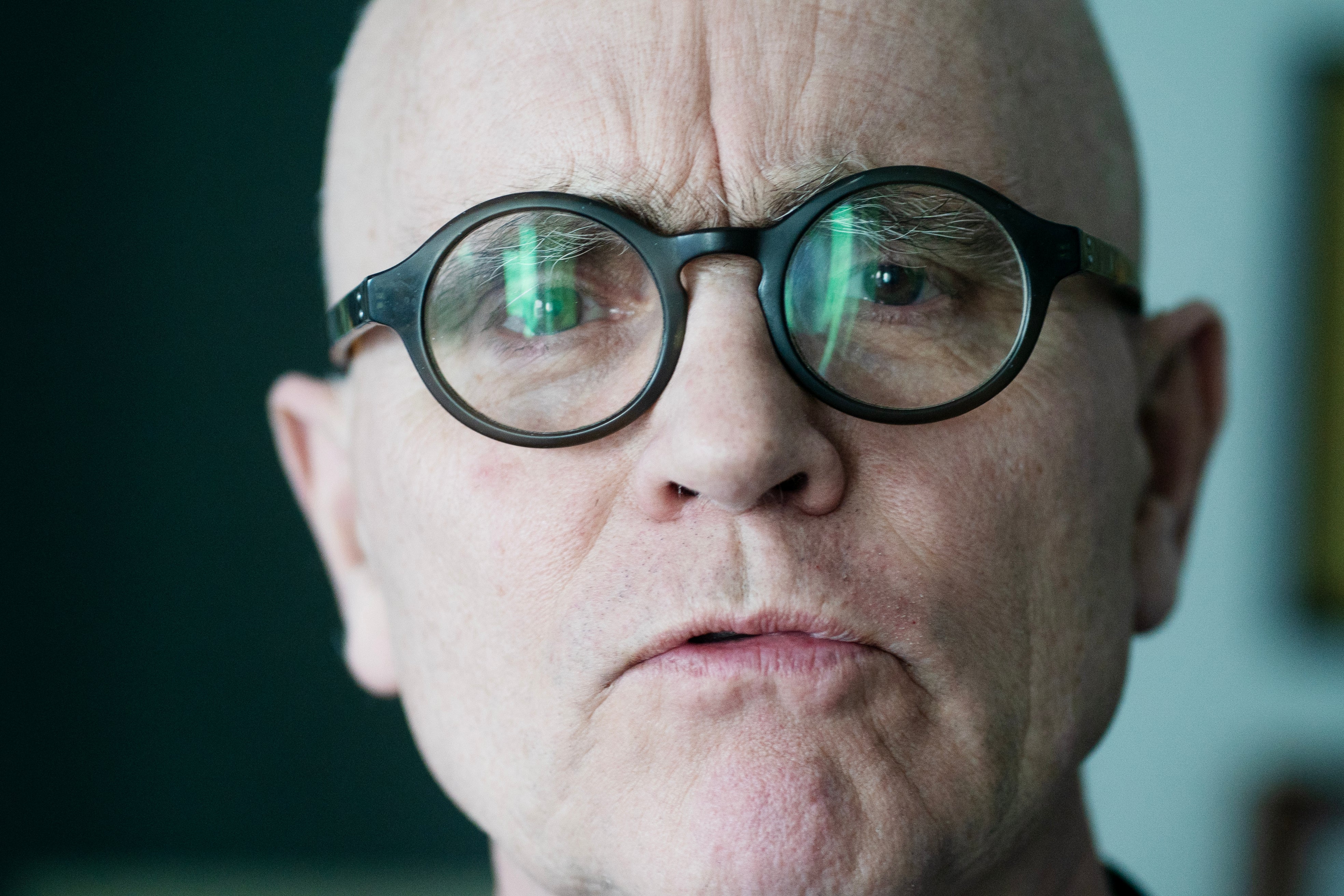 Porträtt av en äldre man med runda svarta glasögon och reflexioner i glasen.