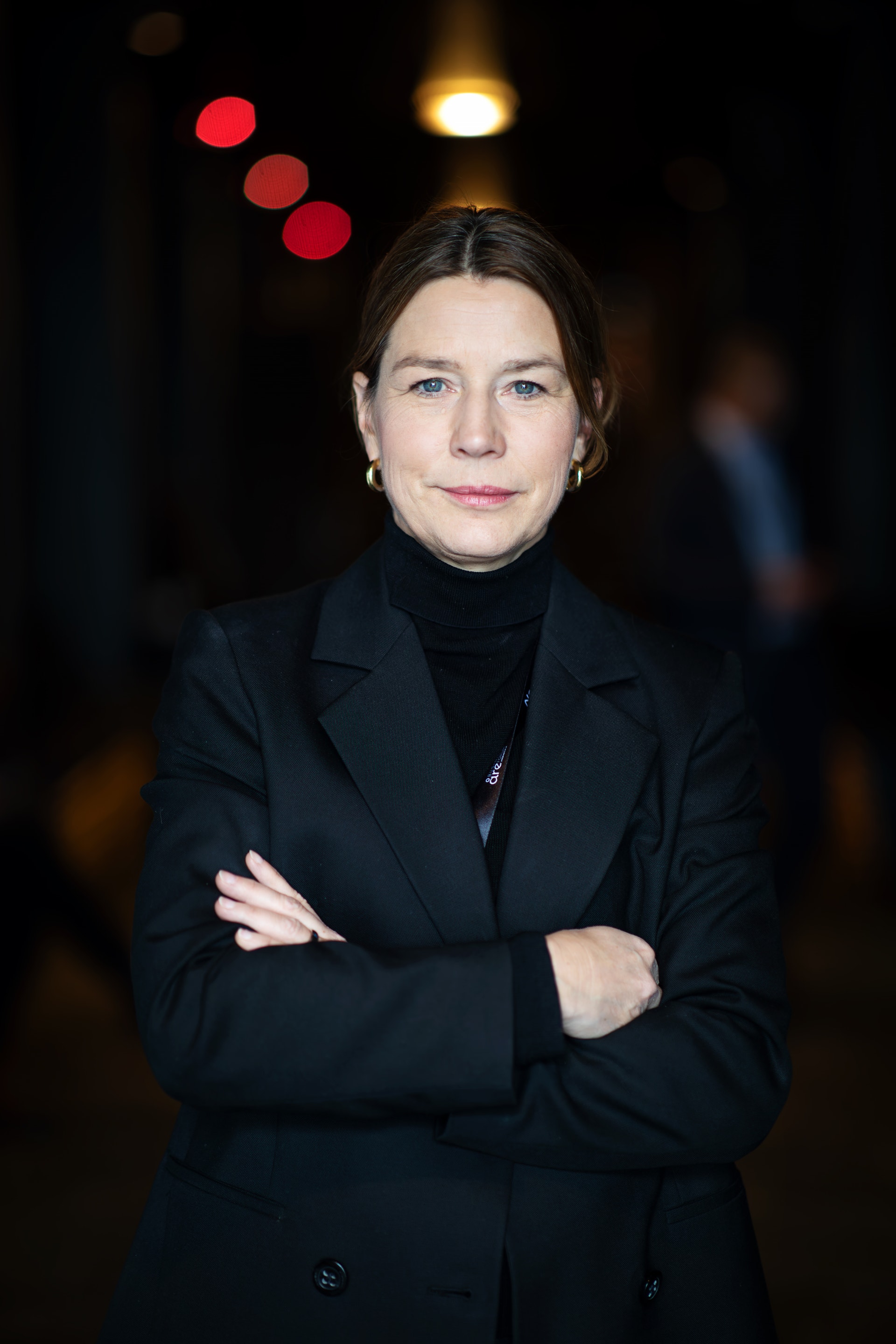 Porträttfoto av Lena Sellgren, chefekonom och analyschef på Business Sweden, i mörk kavaj och polotröja med armarna i kors mot en mörk bakgrund.