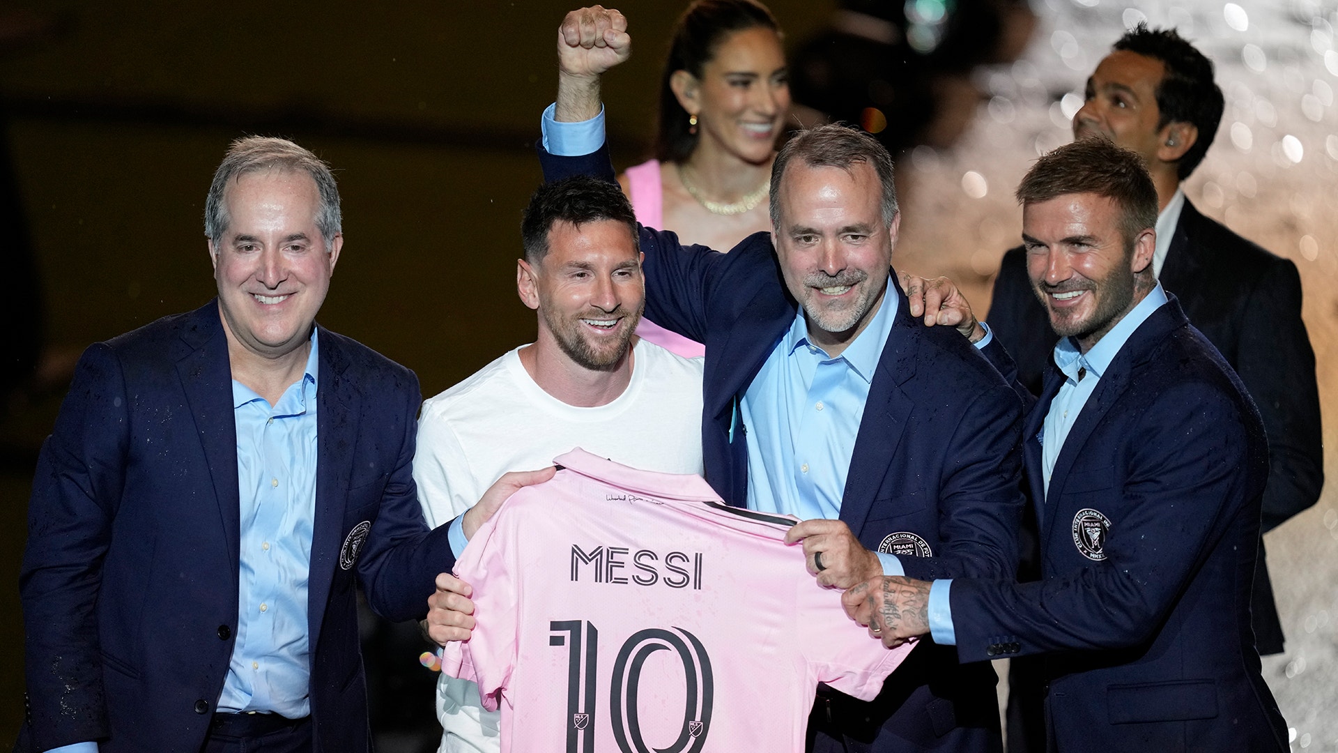 Flera män presenterar en rosa fotbollströja med Messis namn och nummer 10 på en officiell event.