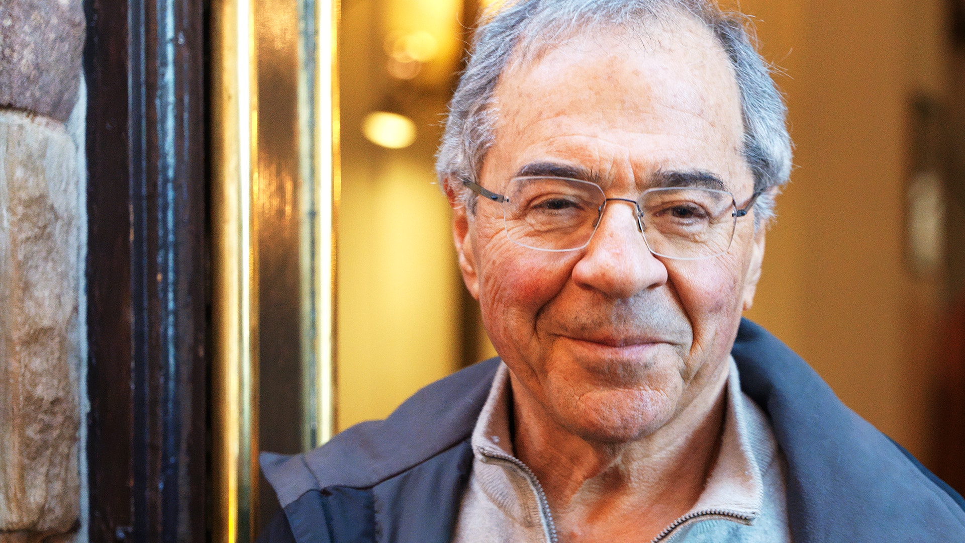 Porträttfoto av en äldre man med grått hår och glasögon