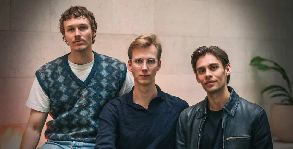 Porträtt av tre män som står tillsammans och tittar mot kameran.