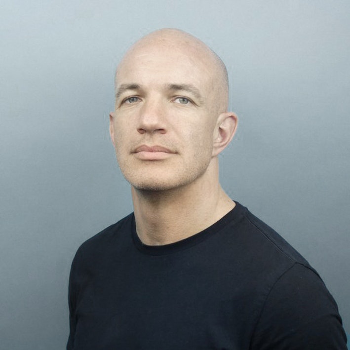 Porträtt av Gregory Thwaites, man i svart t-shirt mot grå bakgrund