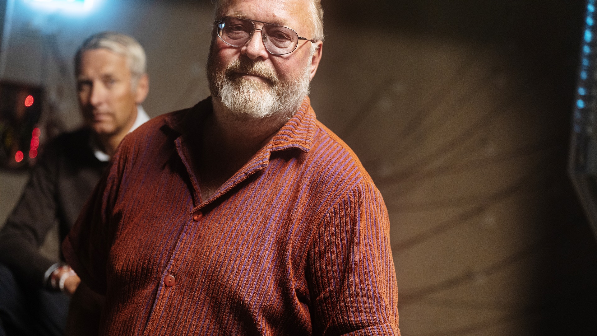 Jan Broman nere i källaren där Dino byggs. Han har på sig en rödskalig skjorta och metalliska glasögon.