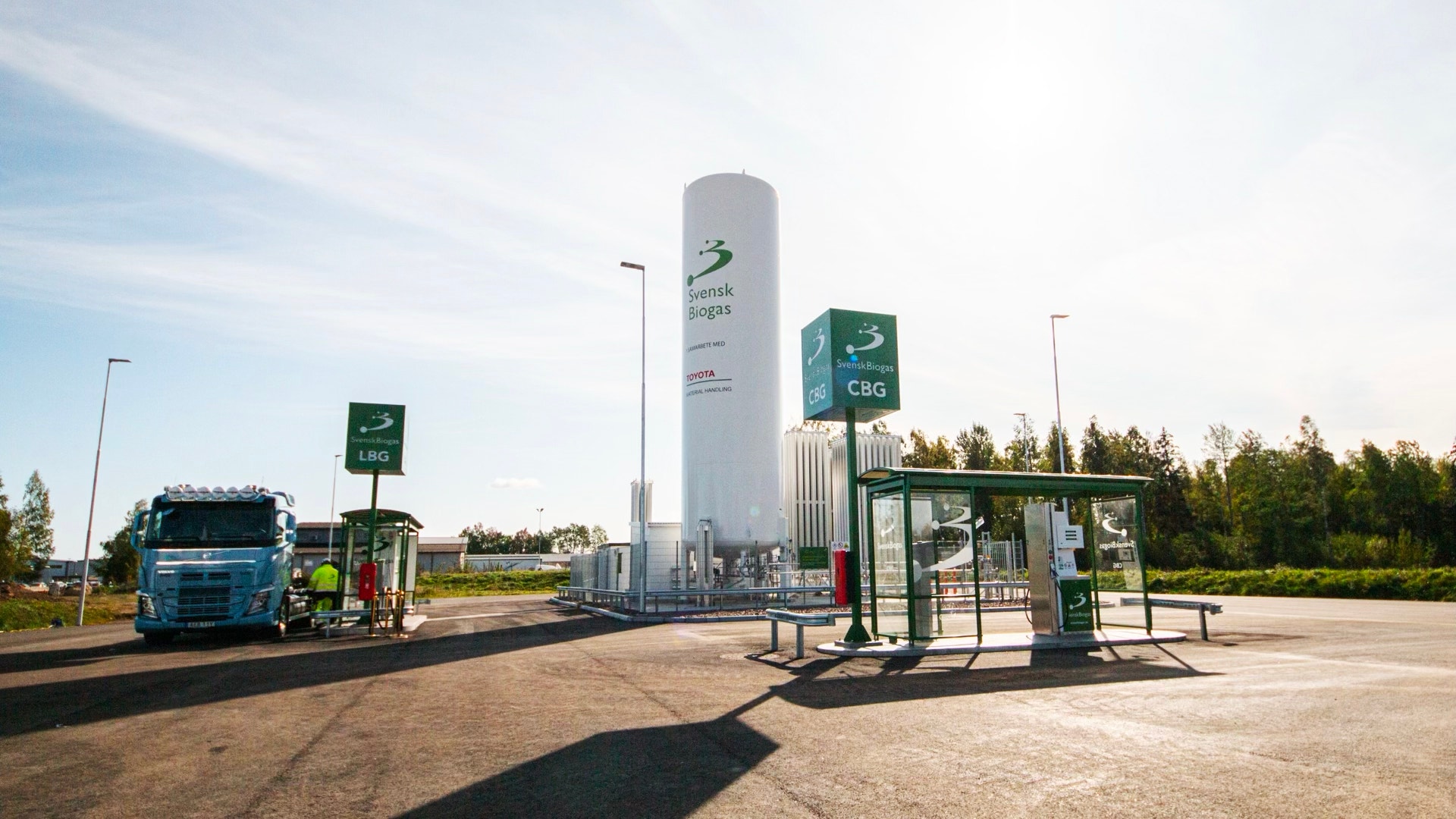 Biogasanläggning med stor lagertank, tanklastbil och tankningsmöjligheter för fordon.