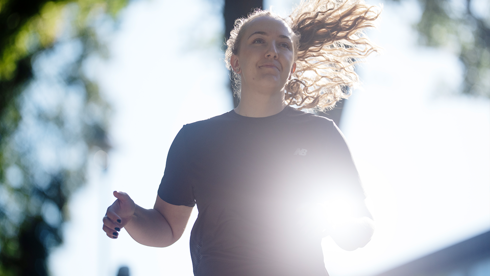 Becca Callton springer i solljuset. Hon har svart t-shirt och håret glittrar i solen. 