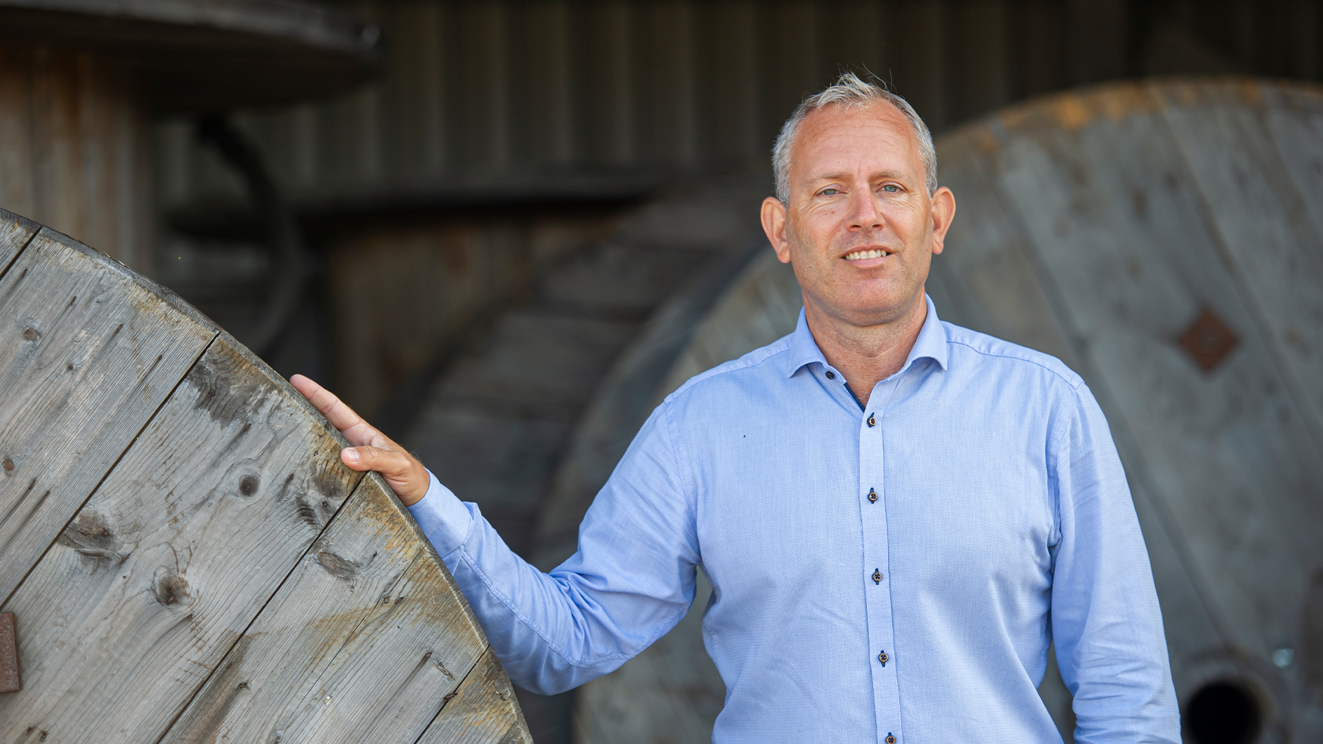 Man i ljusblå skjorta bredvid en stor vindkraftkomponent