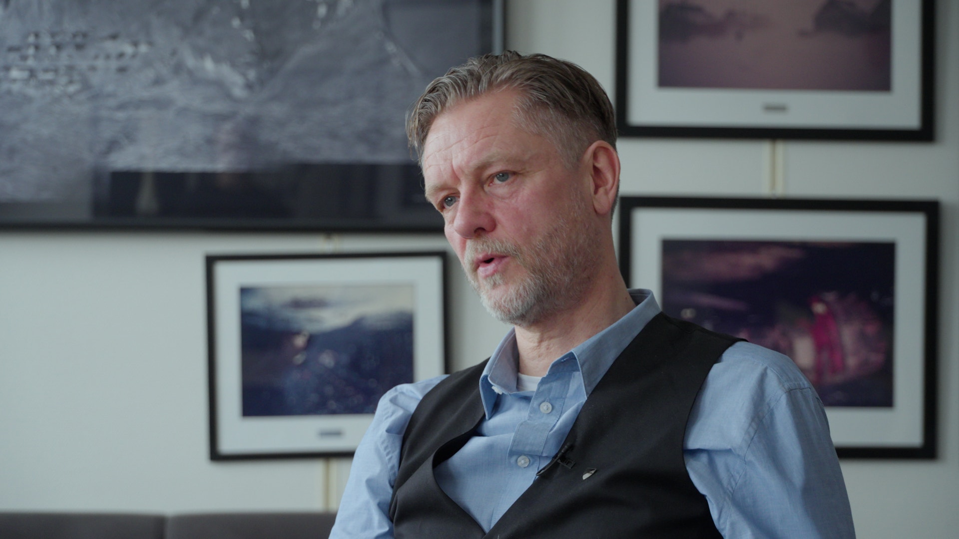 Torje sitter och pratar med reportern, klädd i blå skjorta och svart väst. 