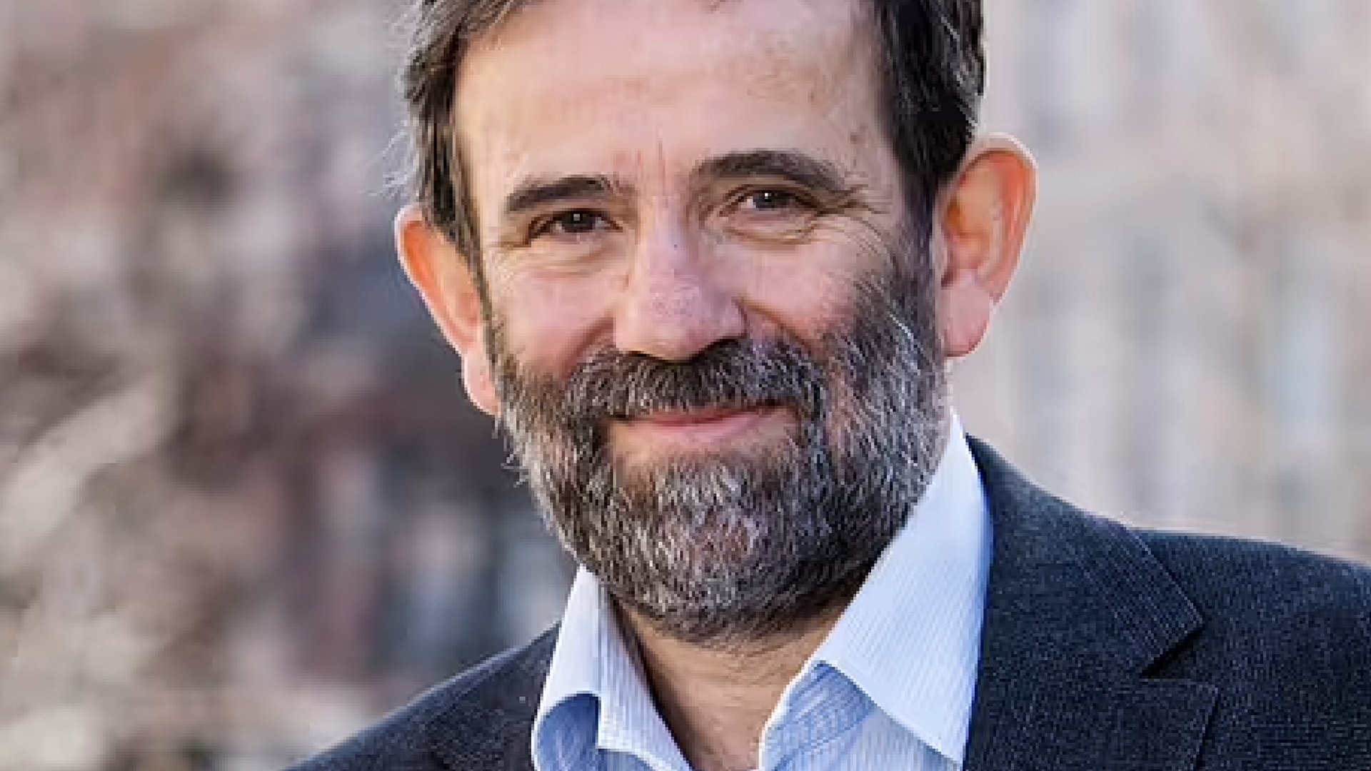 Porträttfoto av en man med skägg i professionell kläder