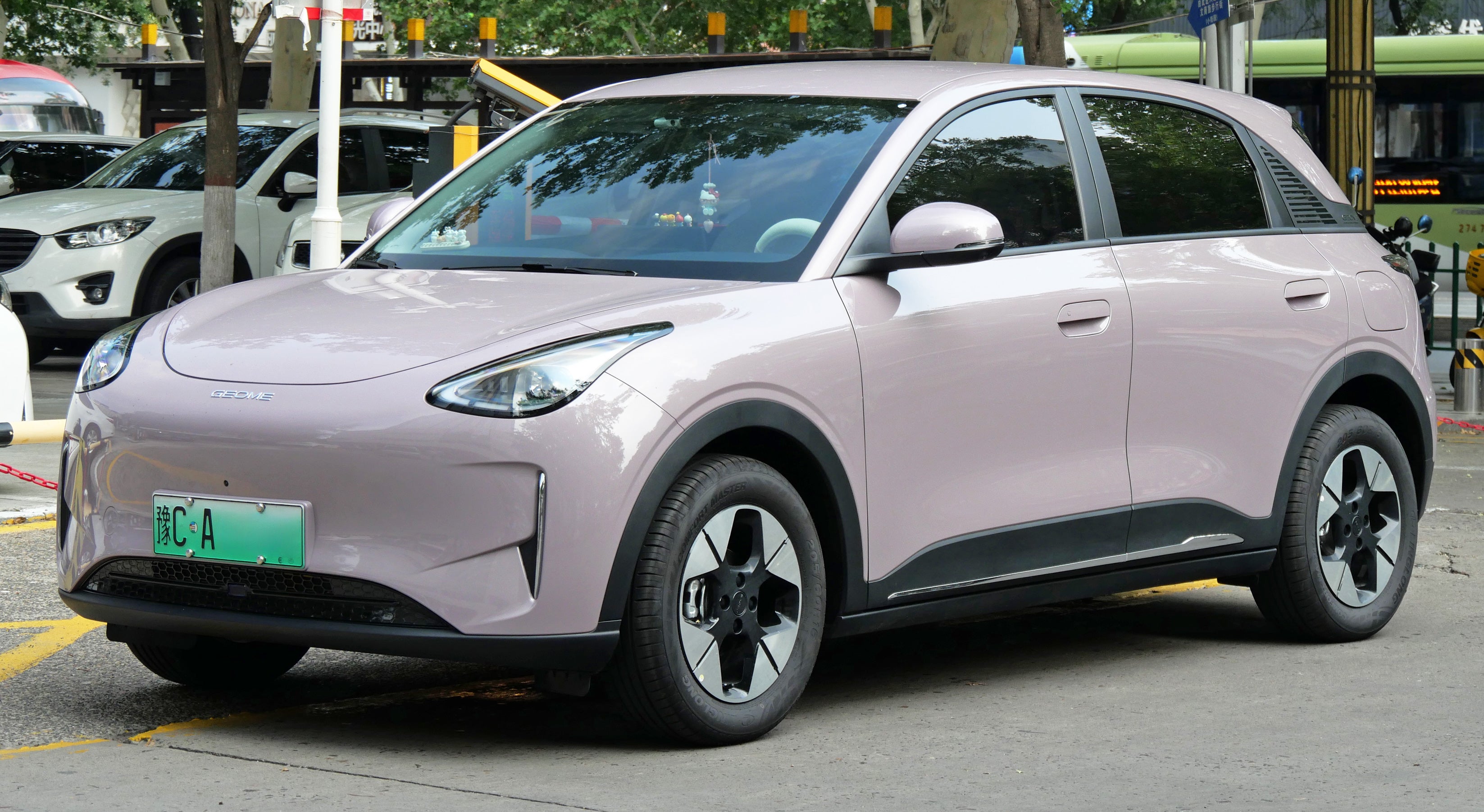 En ljuslila elbil av SUV-modell, sedd snett framifrån, parkerad på en gata.