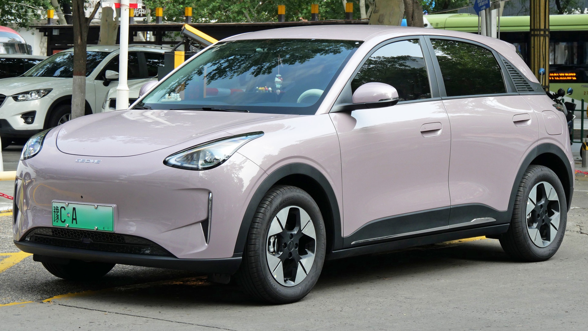 En ljuslila elbil av SUV-modell, sedd snett framifrån, parkerad på en gata.