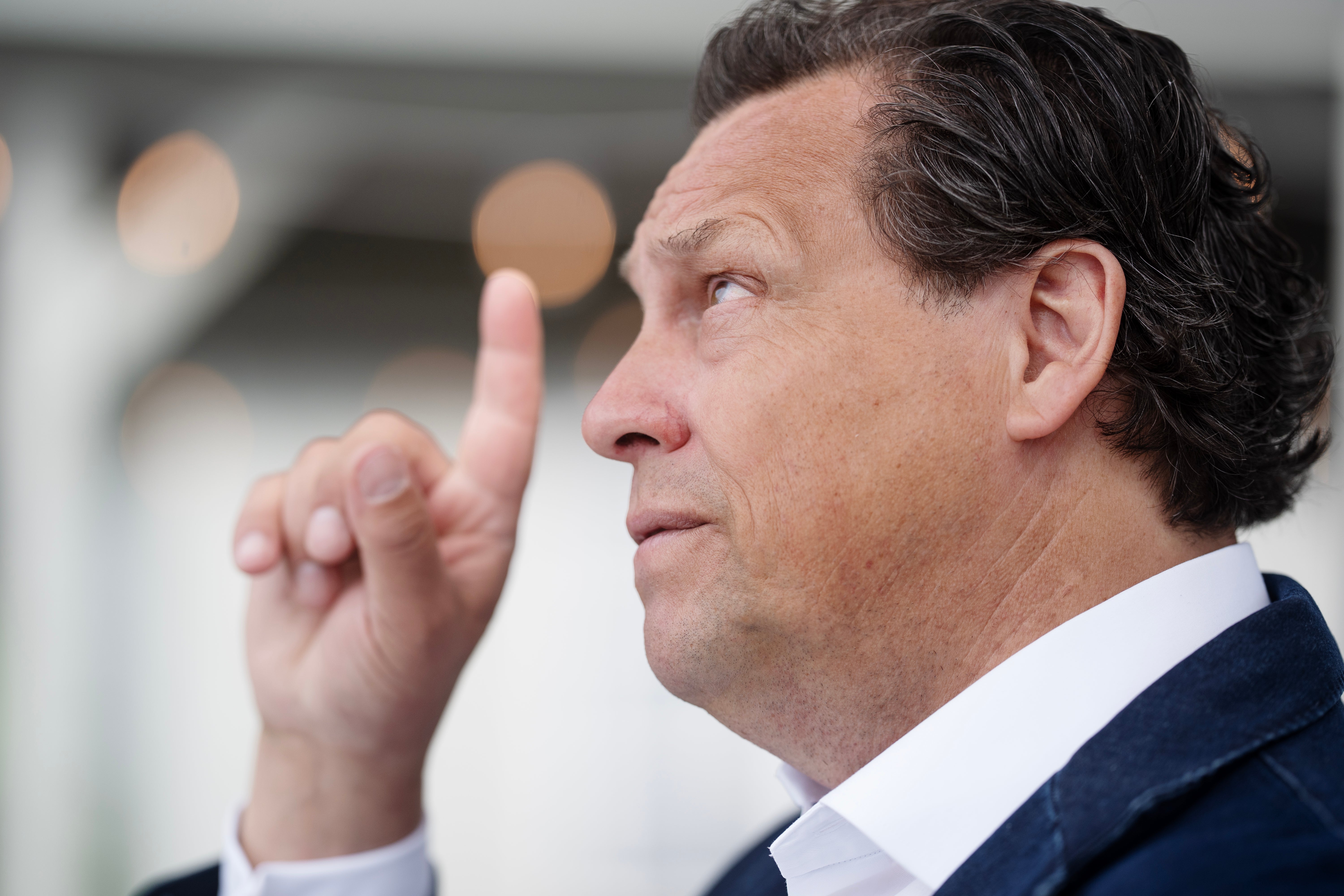 Porträttfoto av en man i kostym som pekar uppåt med sitt finger.