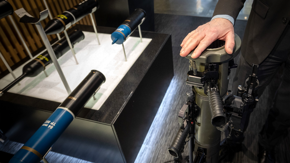 Person håller i en militär eller industriell vapenutrustning vid en utställning.