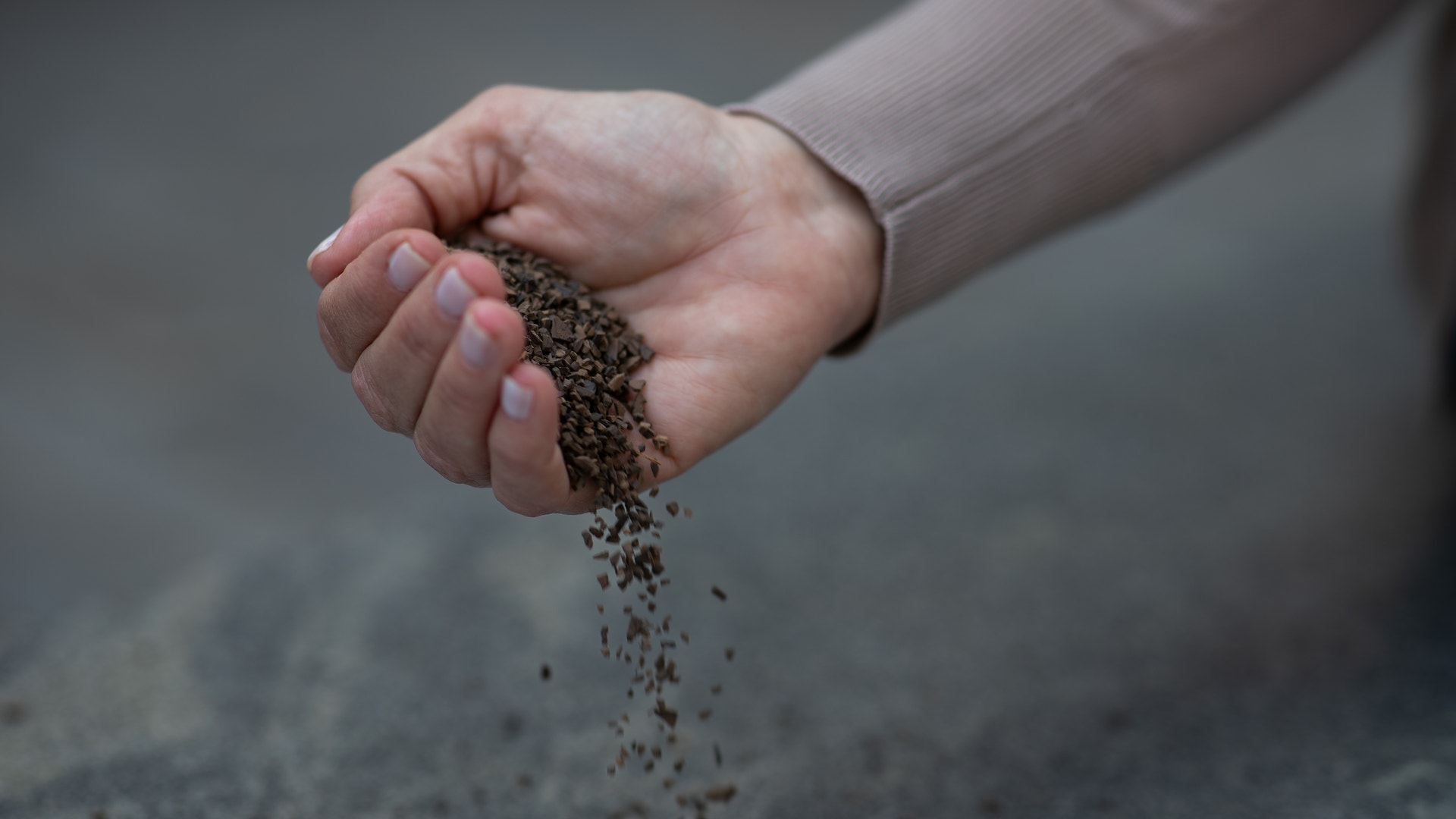 En hand som håller sand som rinner ned mellan fingrarna.