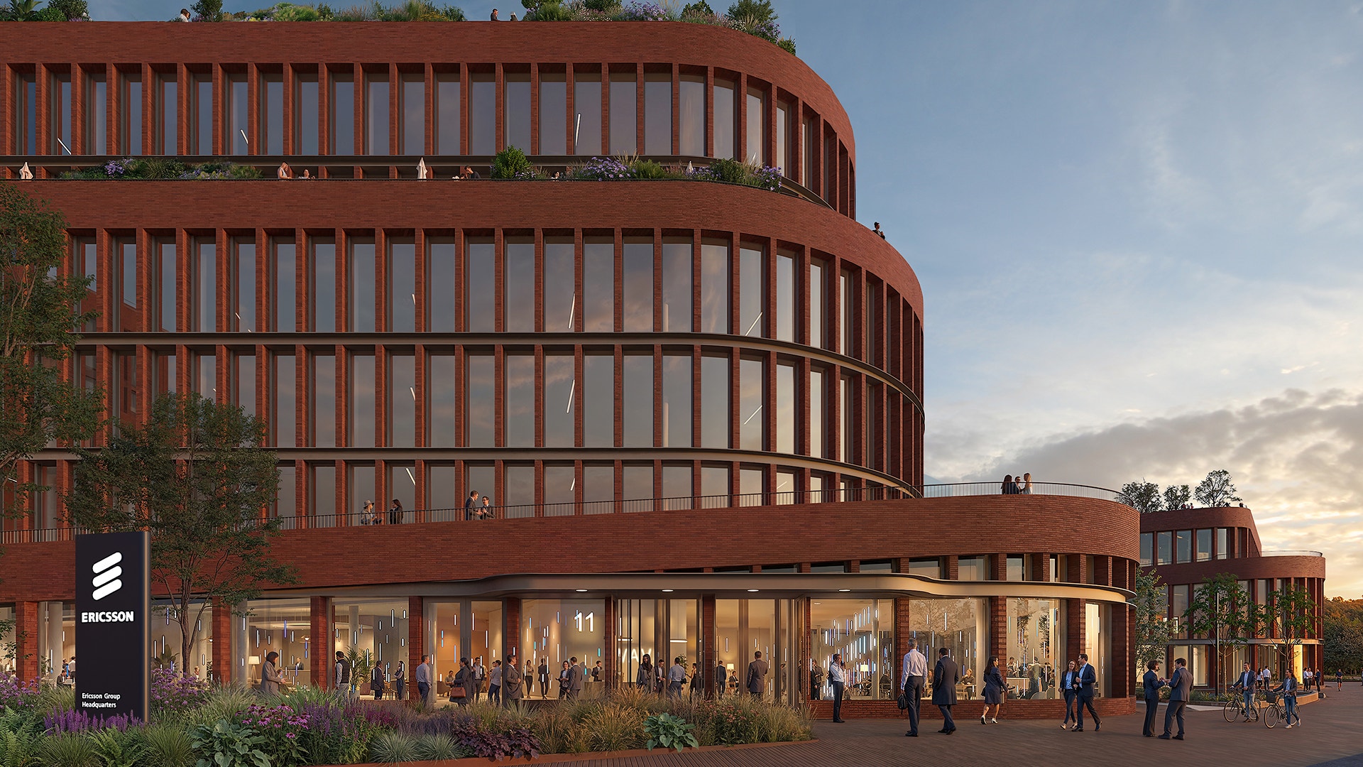 Rendering av en modern röd cirkulär byggnad med flera våningar, vertikala lameller och stora glasfönster i bottenvåningen. Människor och växtlighet framför entrén.