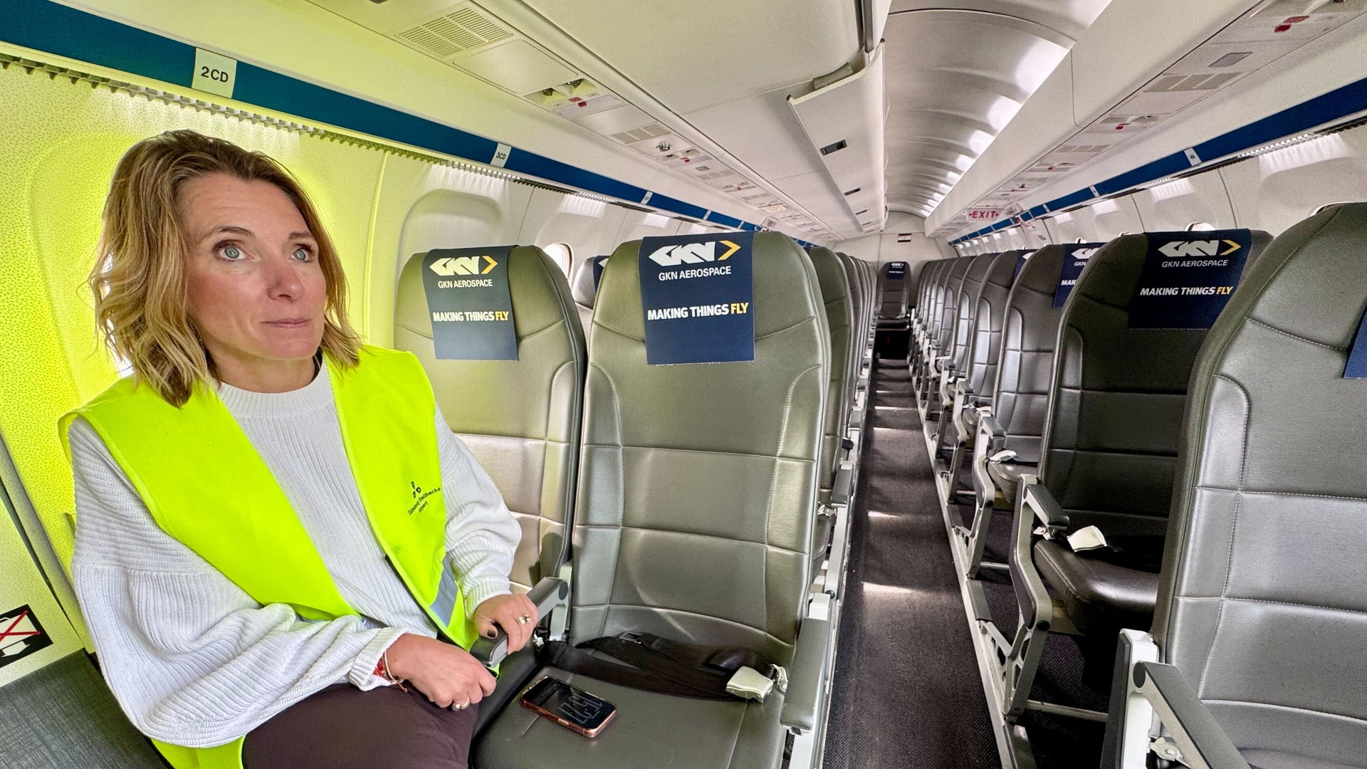 Person i gul säkerhetsvest sitter inne i ett tomt flygplan