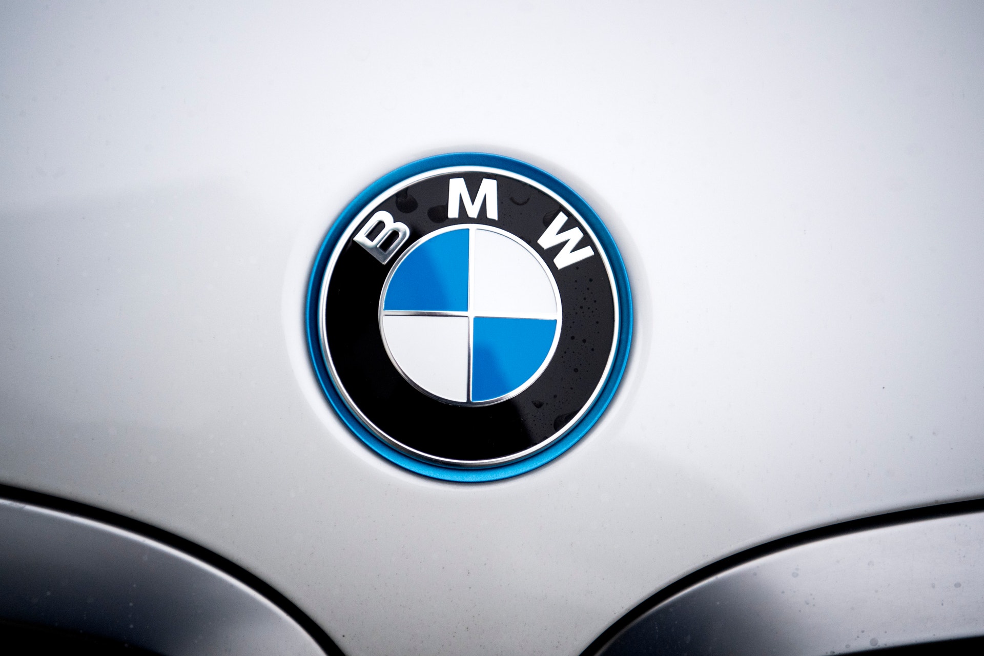 BMW-logotypen med blå och vita fält på en silvergrå bil.