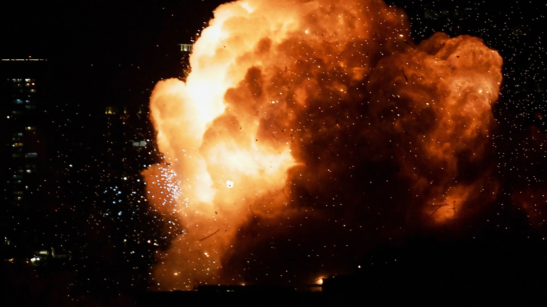 En stor explosion med orange och gula flammor som sprider sig mot en mörk bakgrund.