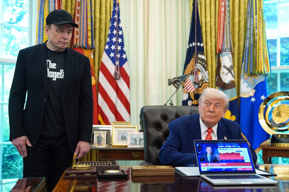 Musk står i Ovala rummet och tittar med besviken min över USA:s president Donald Trumps axel.