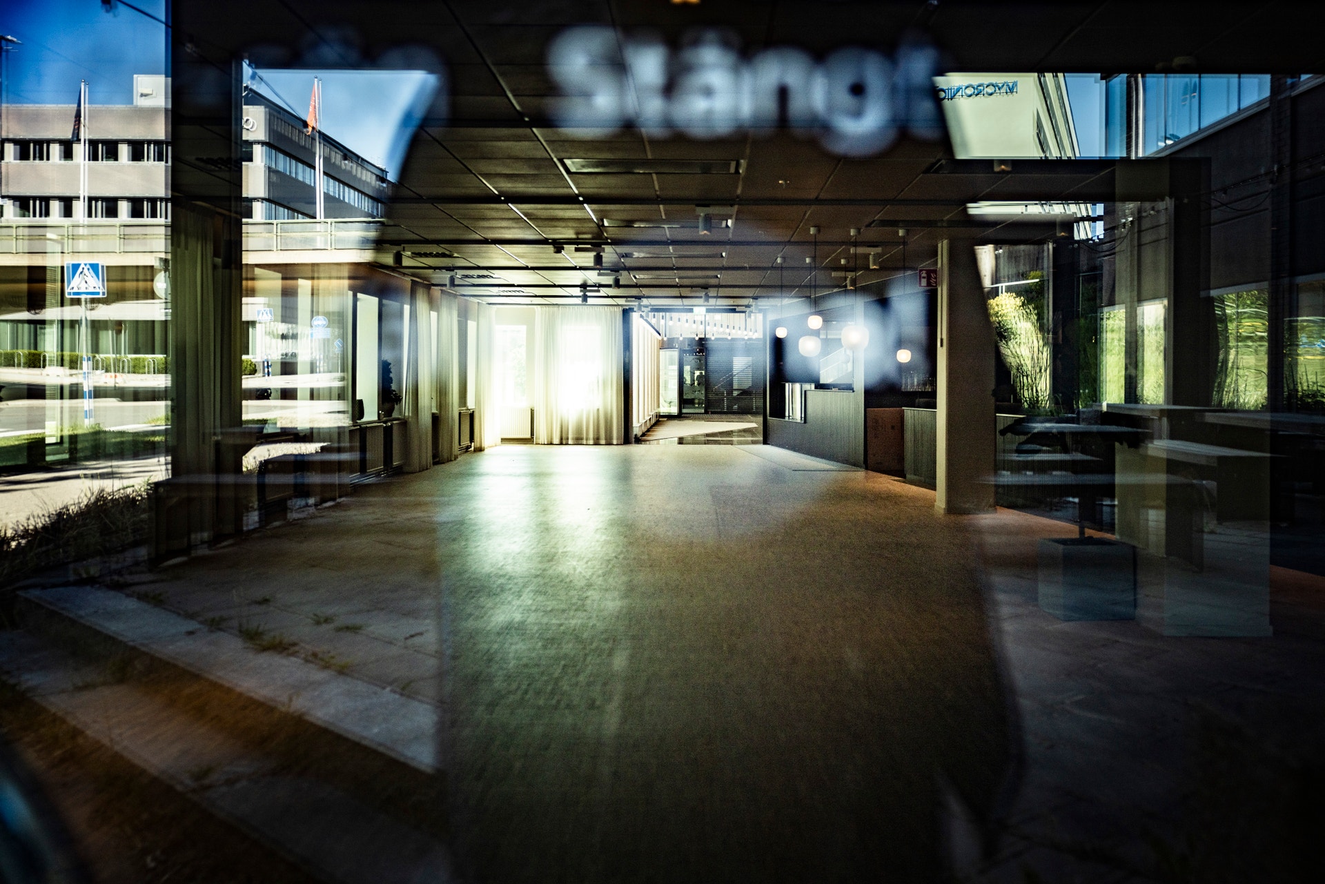 En modern, ljus entréhall med glasväggar och öppet utrymme. Naturligt ljus strömmar in genom stora fönster, och moderna byggnader syns i bakgrunden.