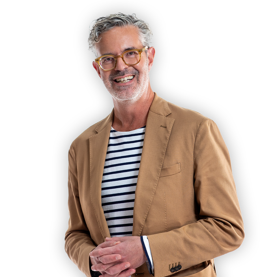 Porträttbild på Henrik Mitelman. Han ler in i kameran. Han bär beige kavaj och en randig tröja. 