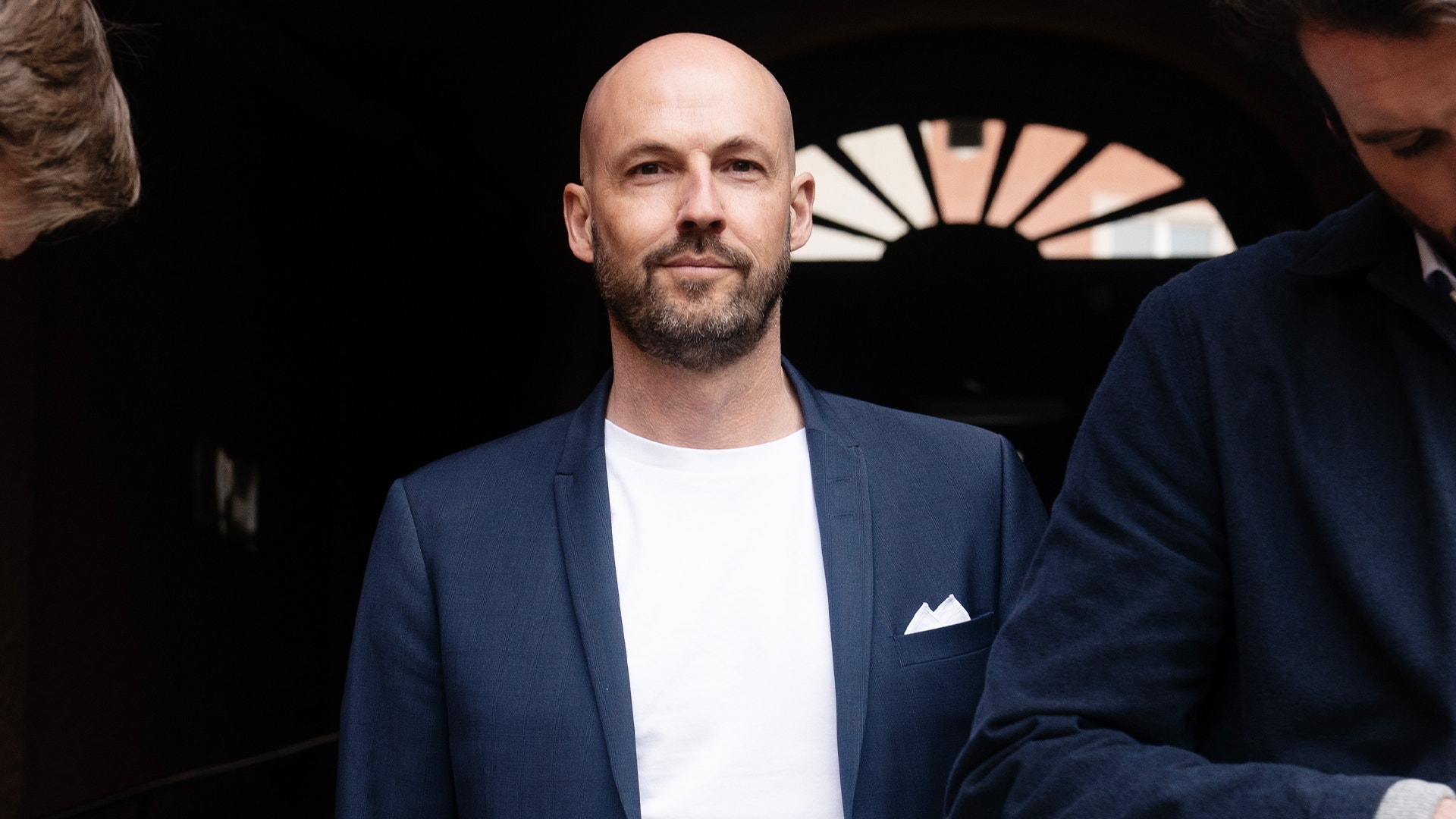 Porträtt av analytiker Martin Blomgren, en man med kort hår och skägg, klädd i mörkblå kavaj och vit skjorta.